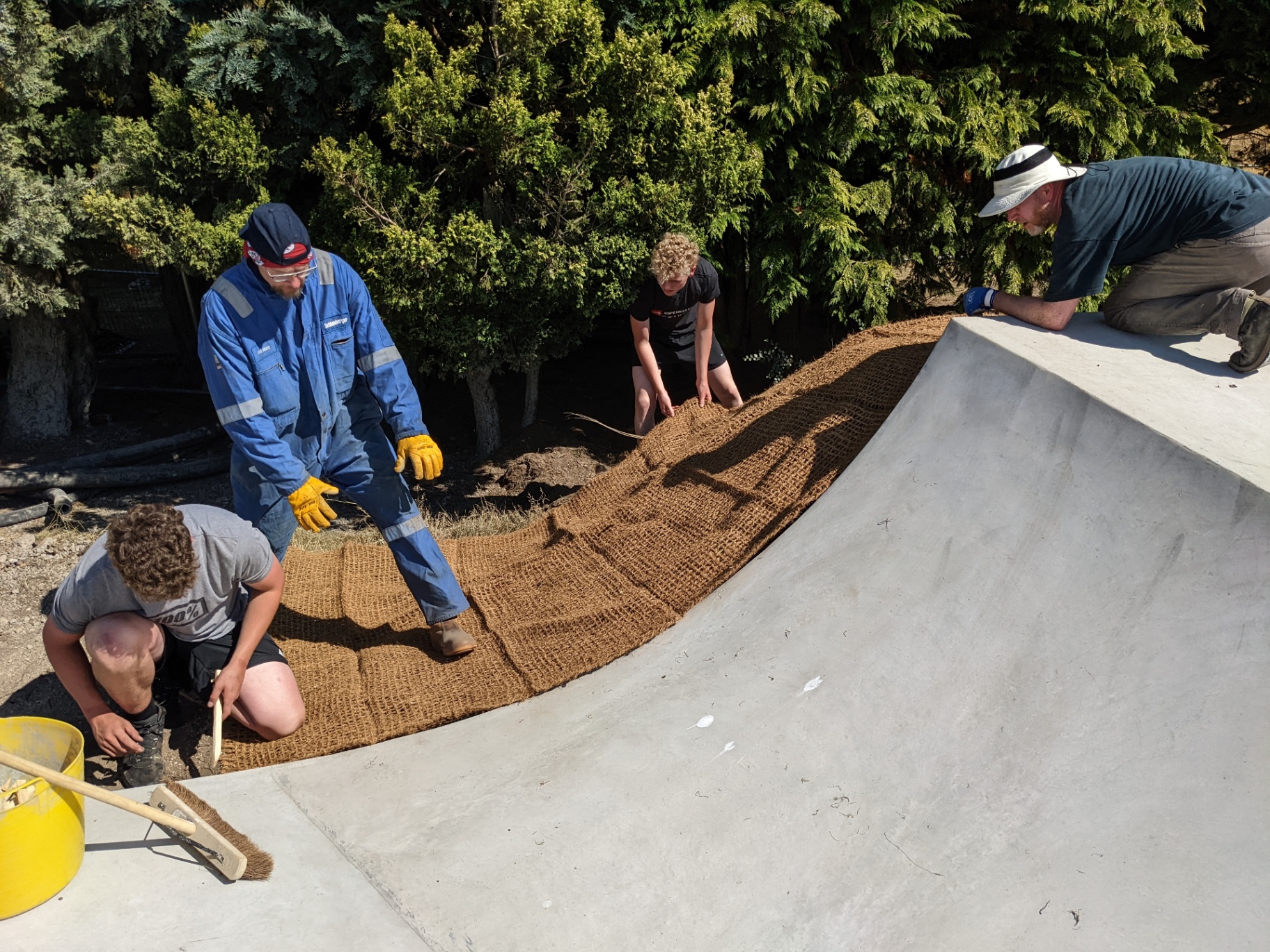 Crew laying coir matting over the bank beside a freshly poured transition